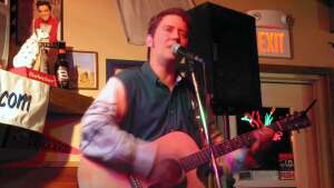 Aaron Traffas singing with an acoustic guitar at Route 40 in Victoria, Kansas