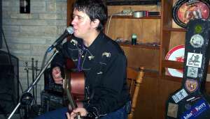 Aaron Traffas singing with an acoustic guitar at Goat House in Manhattan, in northeast Kansas