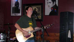 Aaron Traffas singing with an acoustic guitar at R.C. McGraw's in Manhattan, in northeast Kansas