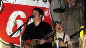 Aaron Traffas singing with acoustic guitar at Blue Goose in Sharon, in south-central Kansas