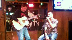 Aaron Traffas singing with an acoustic guitar at Pat's Blue Rib'N in Manhattan, in northeast Kansas