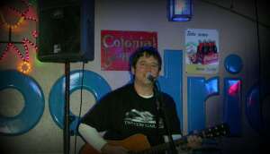 Aaron Traffas singing with an acoustic guitar at Blue Goose in Sharon, in south-central Kansas