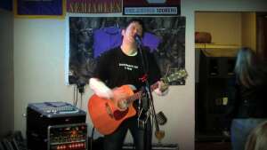 Aaron Traffas singing with an acoustic guitar at Buster's Saloon in Sun City, in south-central Kansas
