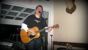 Aaron Traffas singing with an acoustic guitar at Buster's Saloon in Sun City, in south-central Kansas