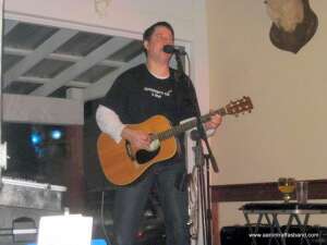 Aaron Traffas singing with an acoustic guitar at Buster's Saloon in Sun City, in south-central Kansas