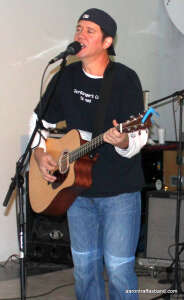 Aaron Traffas singing with an acoustic guitar at Venue Benefit Concert in Medicine Lodge, in south-central Kansas