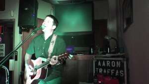 Aaron Traffas singing with an acoustic guitar at Dovie's Bar in Kiowa, in south-central Kansas