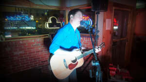 Aaron Traffas singing with an acoustic guitar at Idle Hour in Anthony, in south-central Kansas