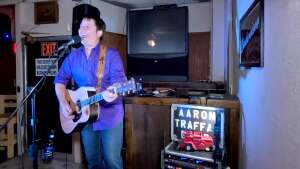 Aaron Traffas singing with an acoustic guitar at Dovie's Bar in Kiowa, in south-central Kansas
