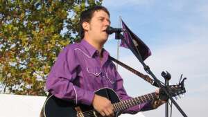 Aaron Traffas singing with an acoustic guitar at Bill Snyder Family Football Stadium in Manhattan, in northeast Kansas