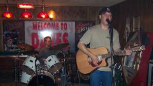 Aaron Traffas singing with acoustic guitar at Dave's Bar in Kiowa, in south-central Kansas