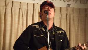 Aaron Traffas singing with an acoustic guitar at Buster's Saloon in Sun City, in south-central Kansas