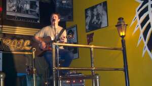 Aaron Traffas singing with an acoustic guitar at Brass Rail in Hays, in central Kansas