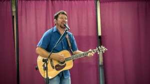 Aaron Traffas singing with an acoustic guitar at Heritage Center in Medicine Lodge, in south-central Kansas